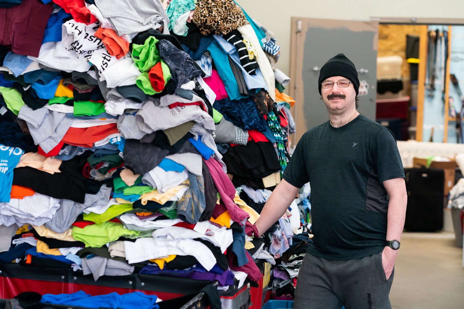 Clothing ministry team member beside donated clothing