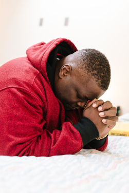 Man in a red sweatshirt praying