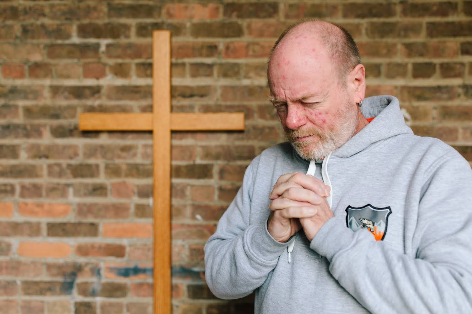 A man praying beside a wooden cross