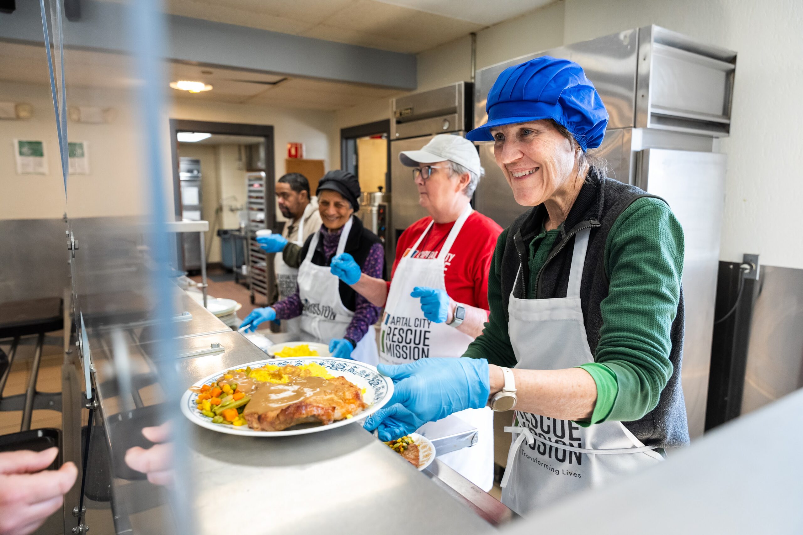 Volunteers serving a prepared meal in the Mission kitchen